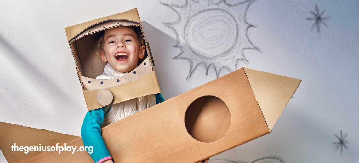 smiling pre-school child playing inside a DIY cardboard astronaut and spaceship costume