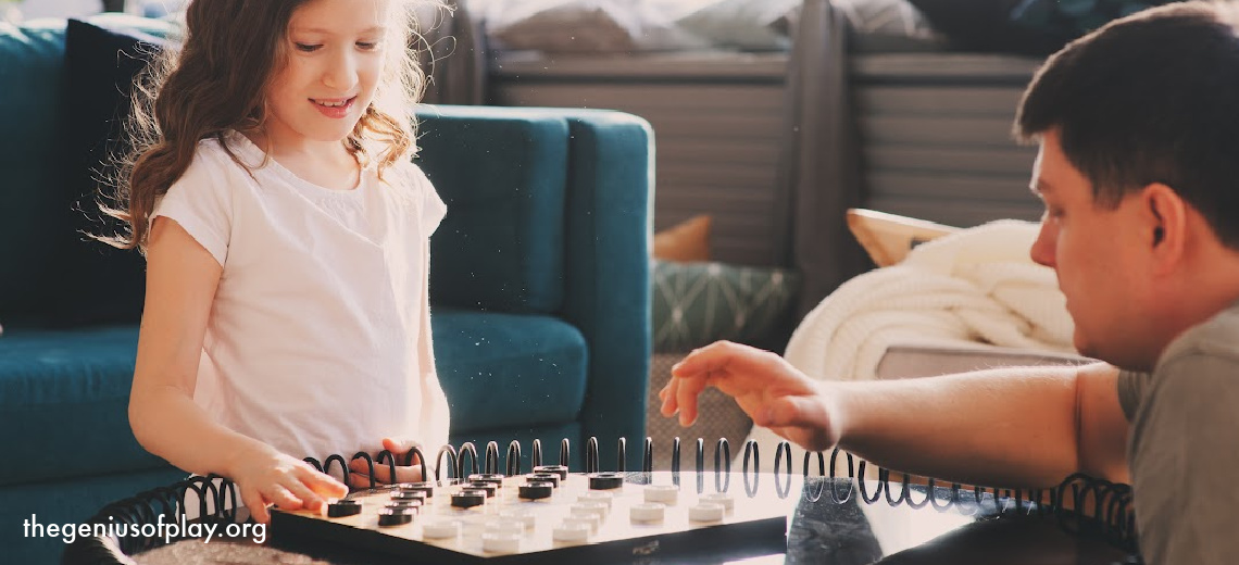 young girl playing the game of checkers with her father