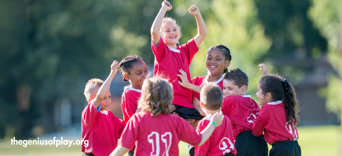 group of multi-cultural elementary school kids celebrating a win on a soccer field 